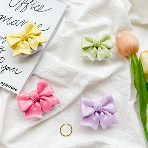 Close-up of colorful resin bow-shaped phone socket grips on a white linen surface