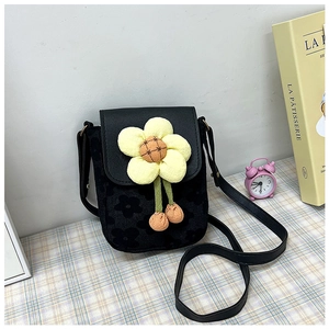 Détail d'un sac bandoulière noir avec texture florale en relief et fleur en peluche jaune