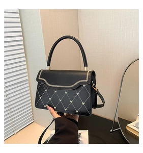 Detail of black quilted leather handbag with green mini hearts and wavy edge flap