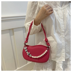 Detail of rose red bag with white pearl chain, silver heart charms, and knotted strap