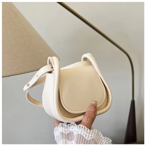 Dettaglio della mini borsa a sella in pelle beige tenuta in mano per le dimensioni