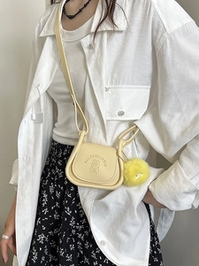 Sacoche selle minimaliste en cuir jaune clair avec détail cartoon et pompon doux