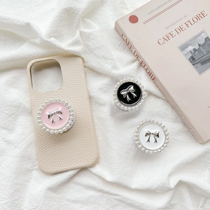 Detail of round phone socket with pearl border and silver bow on beige leather case