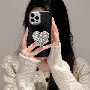 Selfie miroir montrant une coque noire mat avec un grand cœur en strass pour iPhone