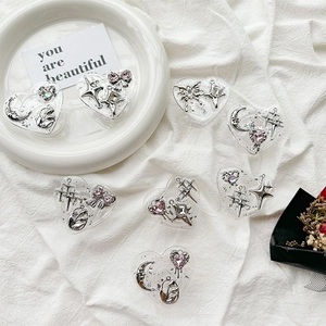 Y2K heart resin phone grip set with silver celestial charms on white textured fabric