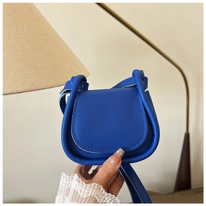 Borsa a sella blu in pelle sintetica liscia tenuta in mano in un ambiente luminoso