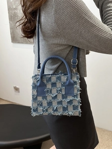 Blaue Denim Handtasche mit Karomuster und Fransen an einem Modell präsentiert