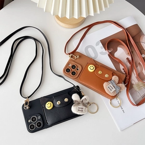 Detail of leather iPhone crossbody case with card slot, smile button and plush rabbit charm