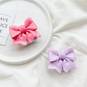 Close-up of pink and purple bow-shaped phone grip stands on white ceramic plate