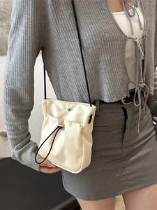 Minimalist off-white mini drawstring phone bag with slim black crossbody shoulder strap