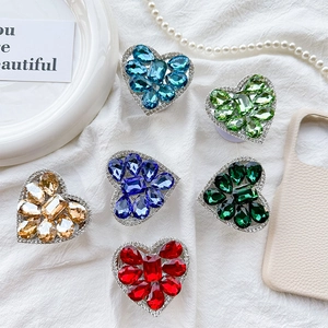 Luxurious crystal heart phone grip holders in six vibrant colors on elegant white fabric