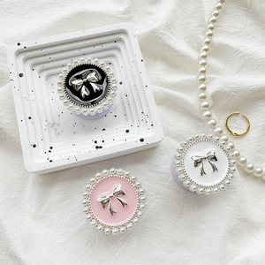 Bow phone grip with pearl trim in black, pink and white on a decorative tray