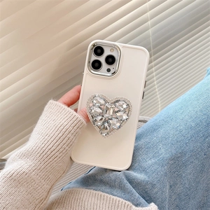 Gros plan d'une coque iPhone crème en silicone avec un cœur luxueux orné de strass brillants