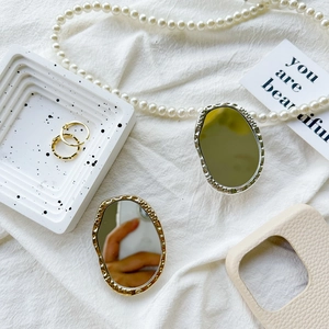 Close-up of oval irregular mirror phone stands with hammered gold and silver textures