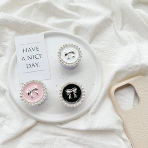 Detail of round phone sockets with pearl edges and metal bows in white pink and black
