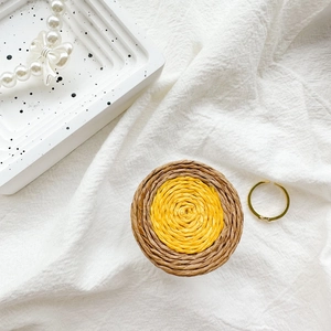 Flat lay of handwoven circular phone socket with chic gold rings and pearl bracelet