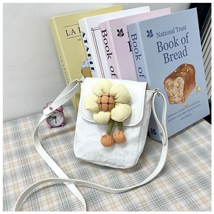 Détail du mini sac bandoulière blanc orné d'une fleur jaune et de pendentifs marrons