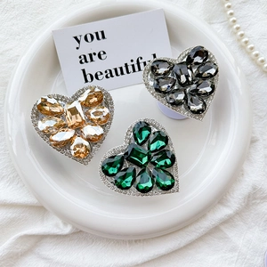 Detailed view of luxurious heart-shaped crystal phone grips in gold, emerald and grey