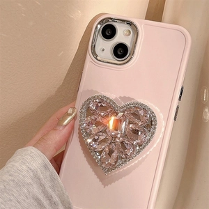 Détail d'une coque iPhone en silicone rose avec support cœur en strass brillant