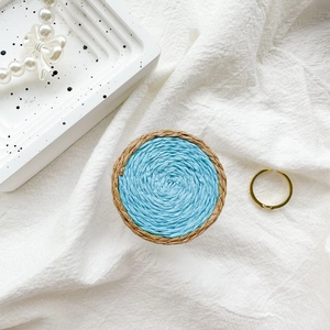 Top-down view of woven collapsible phone grip with blue contrast and natural textures