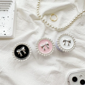 Detail of round phone grips with pearl borders and silver bows in black, pink and white