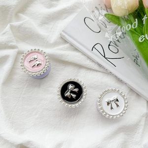 Detail of round phone sockets with pearl borders and silver bow on fabric background