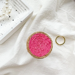 Macro detail of handwoven pink spiral texture on round collapsible phone socket grip