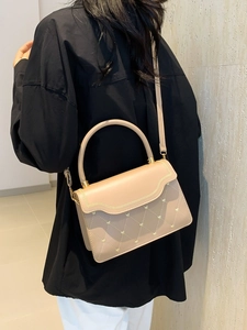 Minimalist beige crossbody bag with quilted heart pattern and gold hardware on a model