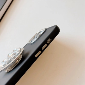 Gros plan d'une coque de téléphone noire mate avec un grand support fleur en strass brillants