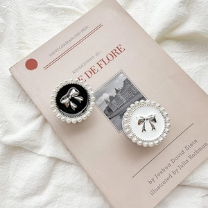 Close-up of pearl-rimmed phone grip with a silver bow tie on a vintage book