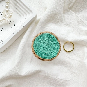 Detail of hand-woven color-block circular phone grip on textured white fabric