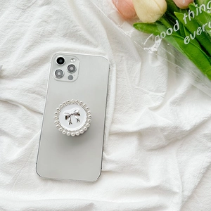 Bow pearl phone grip stand with retractable circular design on a grey smartphone