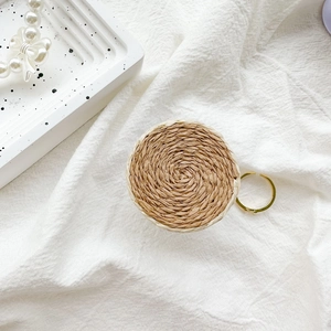 Close-up of circular woven phone grip with natural straw texture and gold metal ring hook