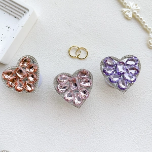 Detailed view of luxury heart-shaped rhinestone phone grips in pink, peach, and purple