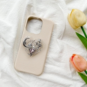 Detail of cream leather phone case with silver moon and pink heart gem on fabric