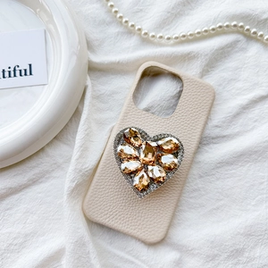 Close-up of heart-shaped rhinestone embellishment on beige leather phone case