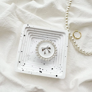 Close-up of pearl-rimmed circular phone grip with silver bow on white tray