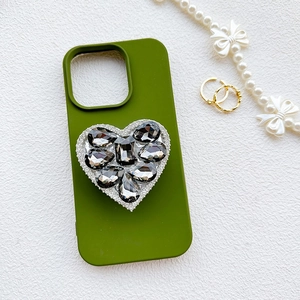 Luxury green phone case with a large diamond heart grip on a white texture background