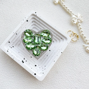 Detail of luxury heart phone grip with green crystal gems and shimmering diamonds
