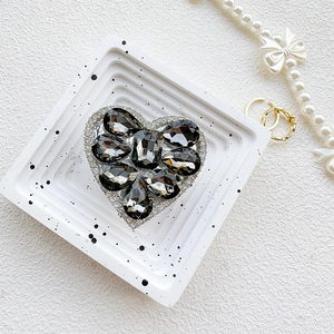 Macro detail of luxury heart-shaped phone grip with gray crystals and white rhinestones