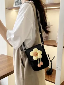 Sac bandoulière noir chic orné d'une grande fleur jaune et de pompons colorés
