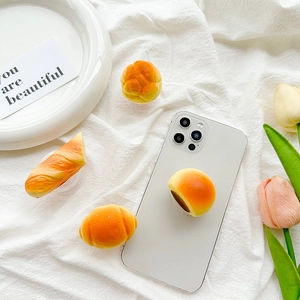 3D realistic bread phone grip set with croissant and bun designs on a white phone