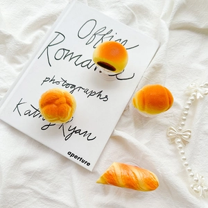 Close-up of realistic 3D bread-shaped phone sockets on white linen fabric and art book