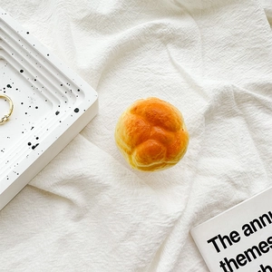 Close-up of a 3D bread-shaped phone grip with a realistic texture on a white cloth
