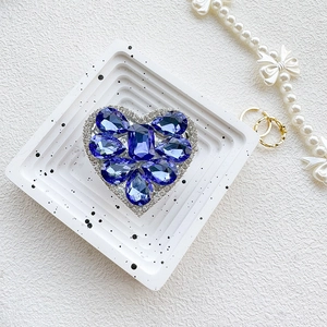Macro detail of luxury heart-shaped phone grip featuring deep blue crystals and rhinestones