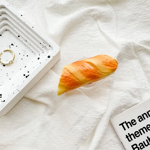 Macro detail of 3D croissant shaped phone grip with realistic golden puff pastry texture