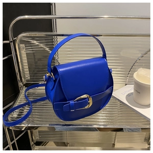 Detail of royal blue saddle bag showing smooth leather texture and gold buckle