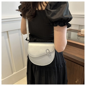 Detail of silver half-moon saddle bag with metallic finish and oval metal clasp