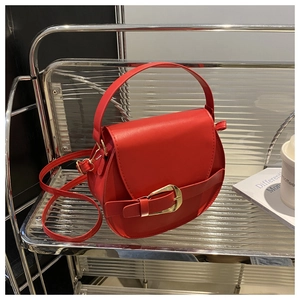 Detail of red saddle bag featuring a golden horseshoe clasp on metallic display