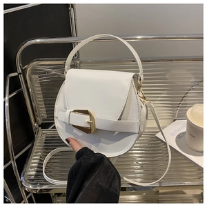 Detail of white leather saddle bag with gold metal buckle and adjustable shoulder strap
